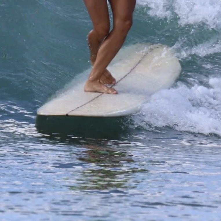 Jambes d'une femme en train de faire un cross steps sur son longboard